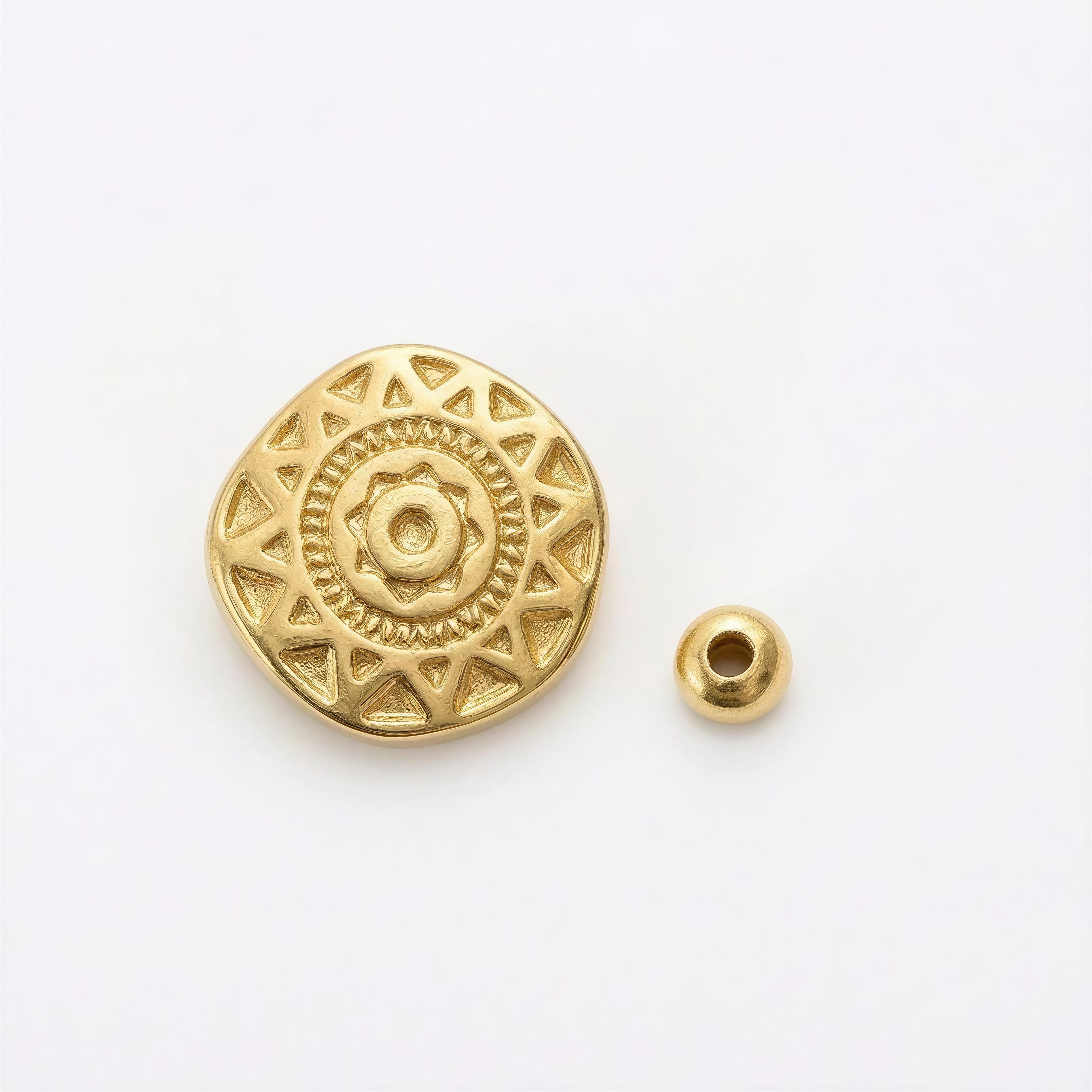 Close-up of a gold-toned round bead with a sun-inspired engraved pattern and a smaller plain round bead, part of the RING - SOLARA collection.