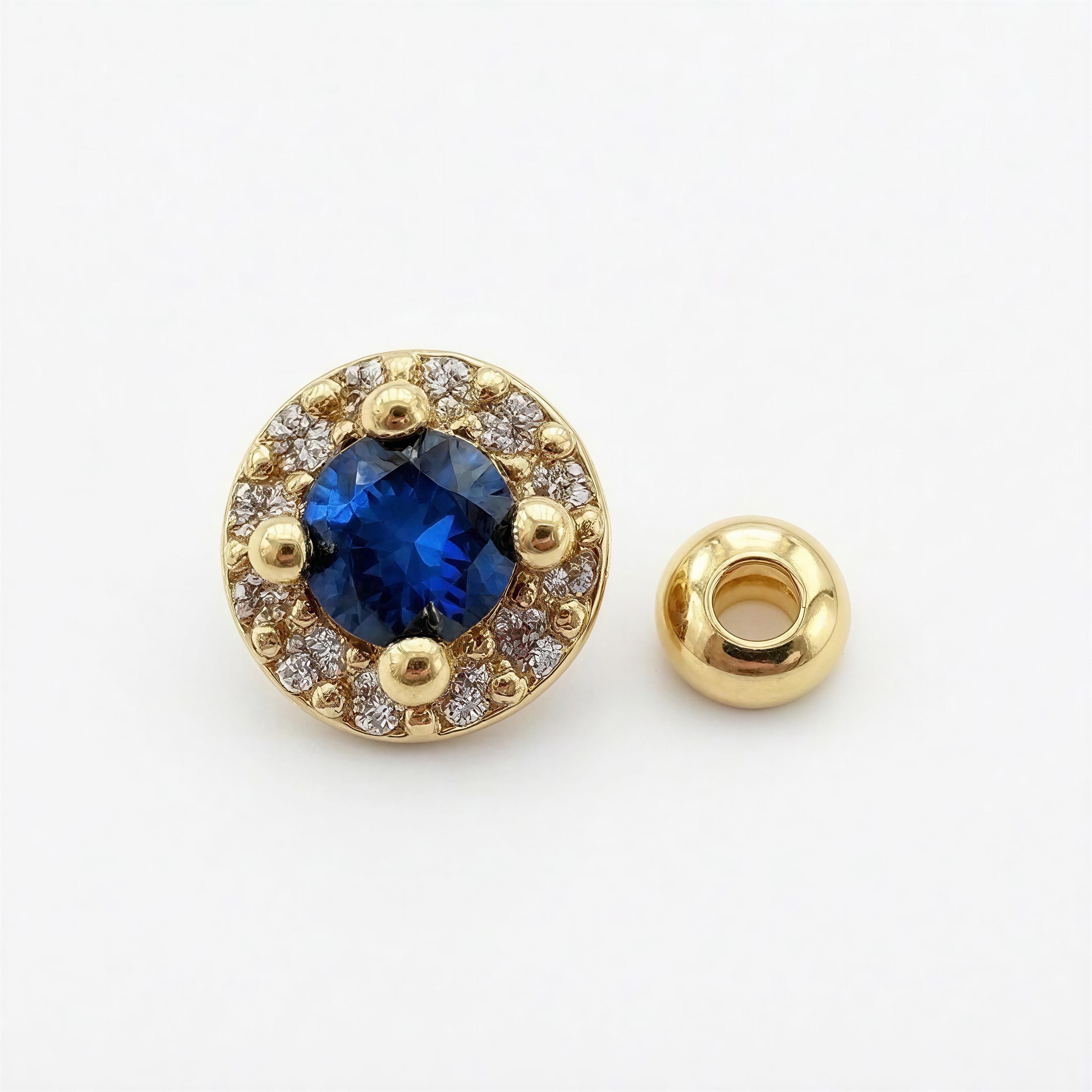 Close-up of a round gold bead featuring a deep blue sapphire center surrounded by a halo of small clear crystals, part of the XX ÉLÉGANCE - AZURA ROYALE collection.