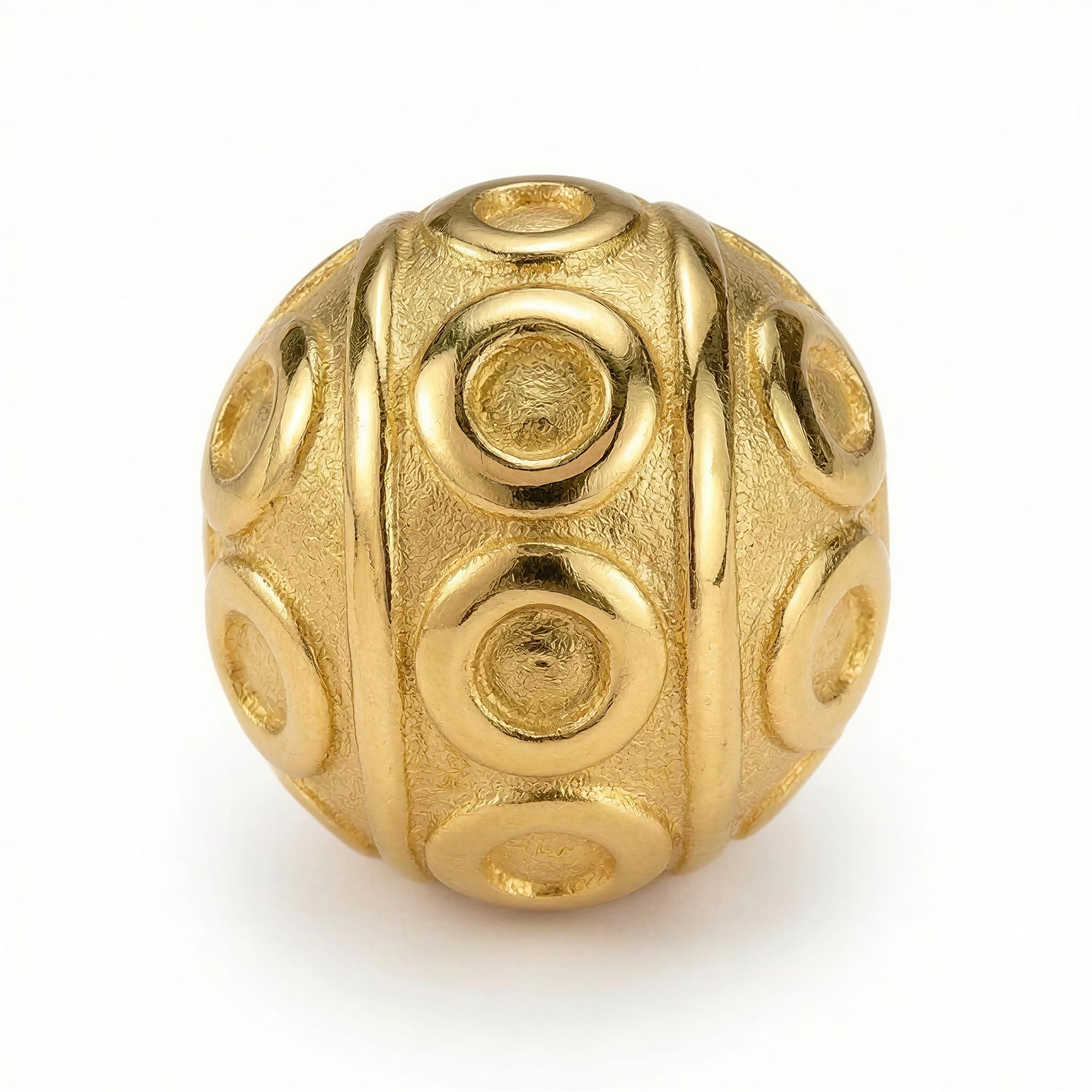 Close-up of a gold bead with raised circular patterns and textured finish, part of the XX ÉLÉGANCE – AURELIA LUXE collection by Atelier X handcrafted luxury jewelry.
