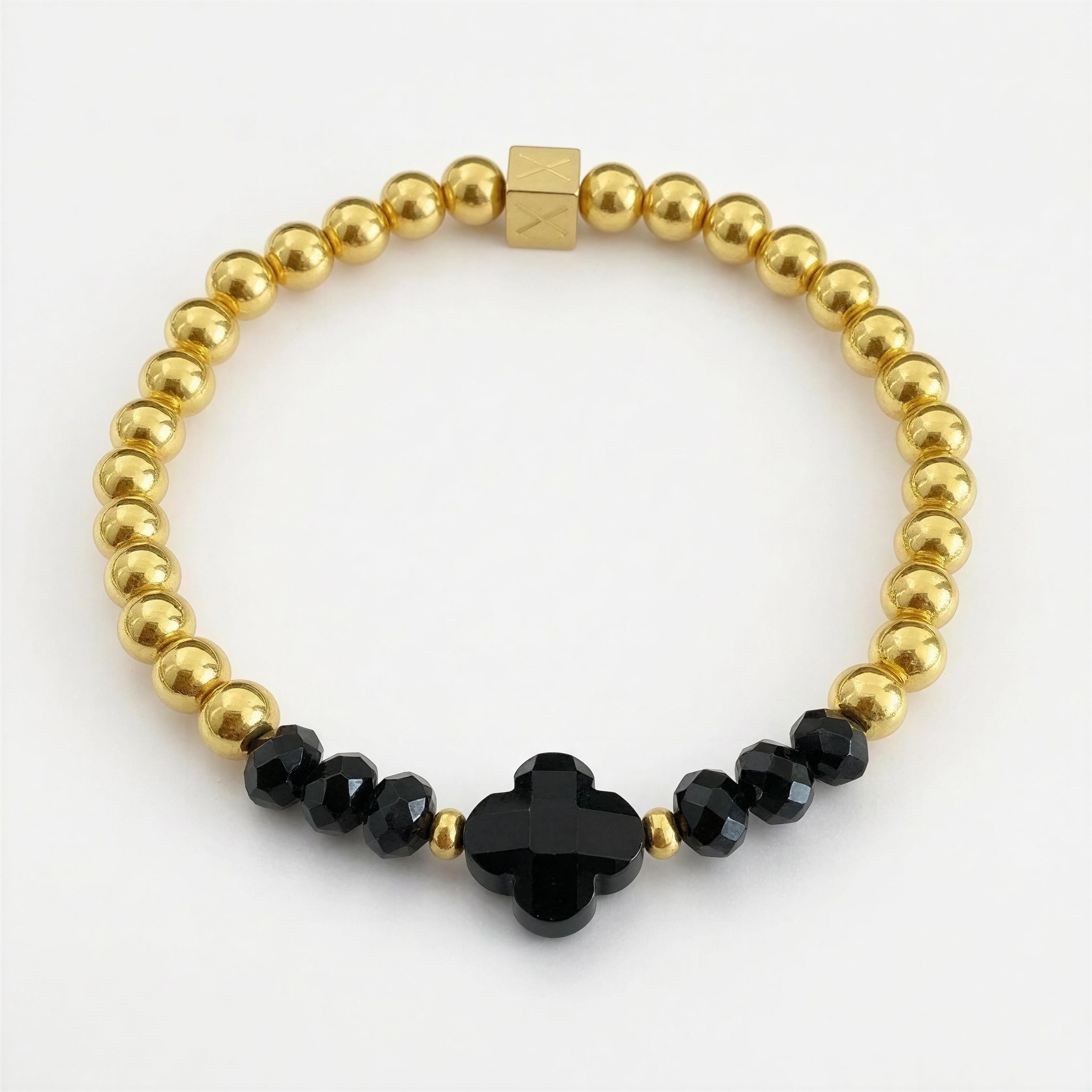 XX ÉLÉGANCE - Noir Fortuna bracelet featuring polished gold beads and faceted black beads with a central black clover-shaped bead, showcasing luxury handcrafted jewelry.