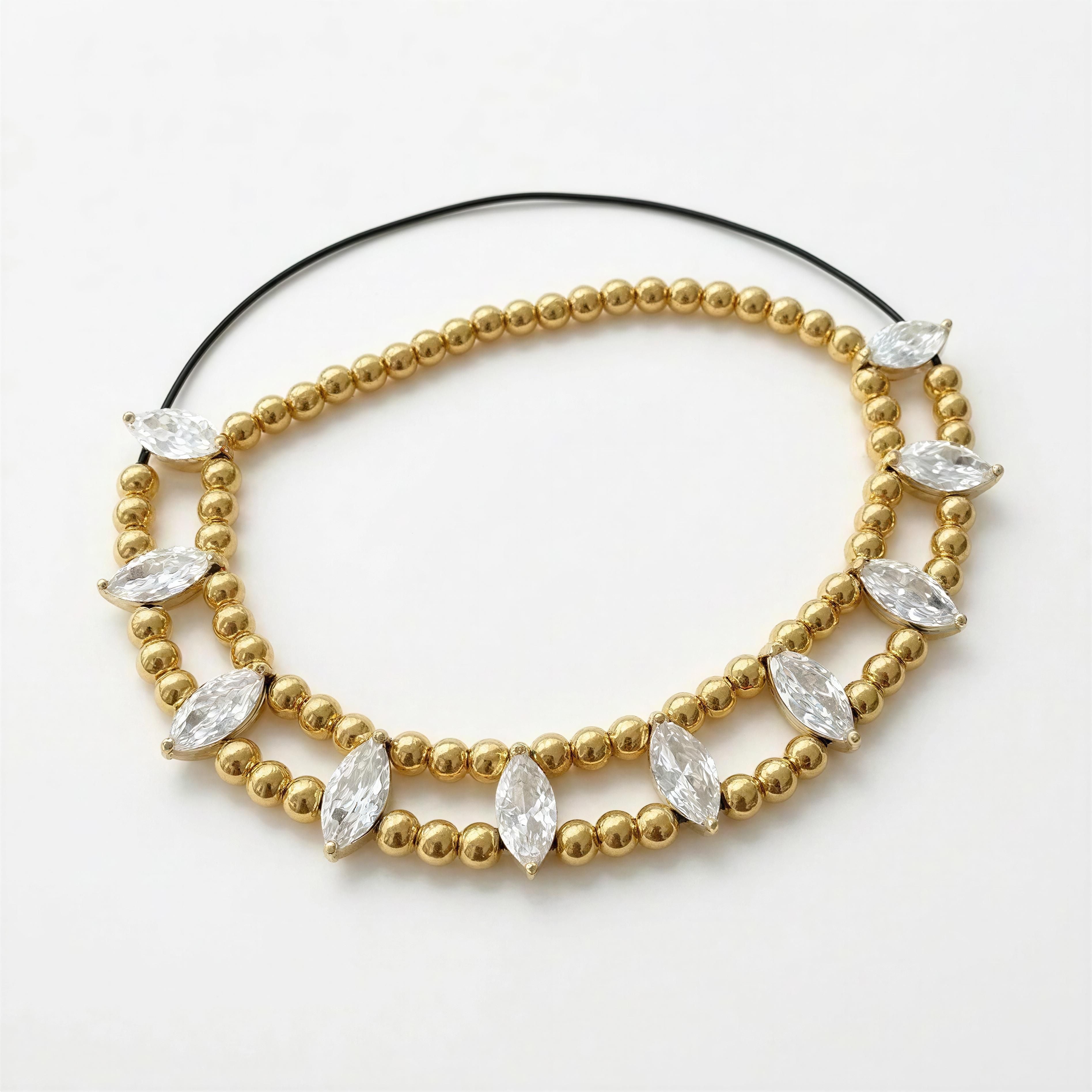 XX ÉLÉGANCE – LUMIÈRE D’OR features a delicate designer bracelet with gold beads accented by marquise-cut clear crystals for a handcrafted luxury jewelry look.