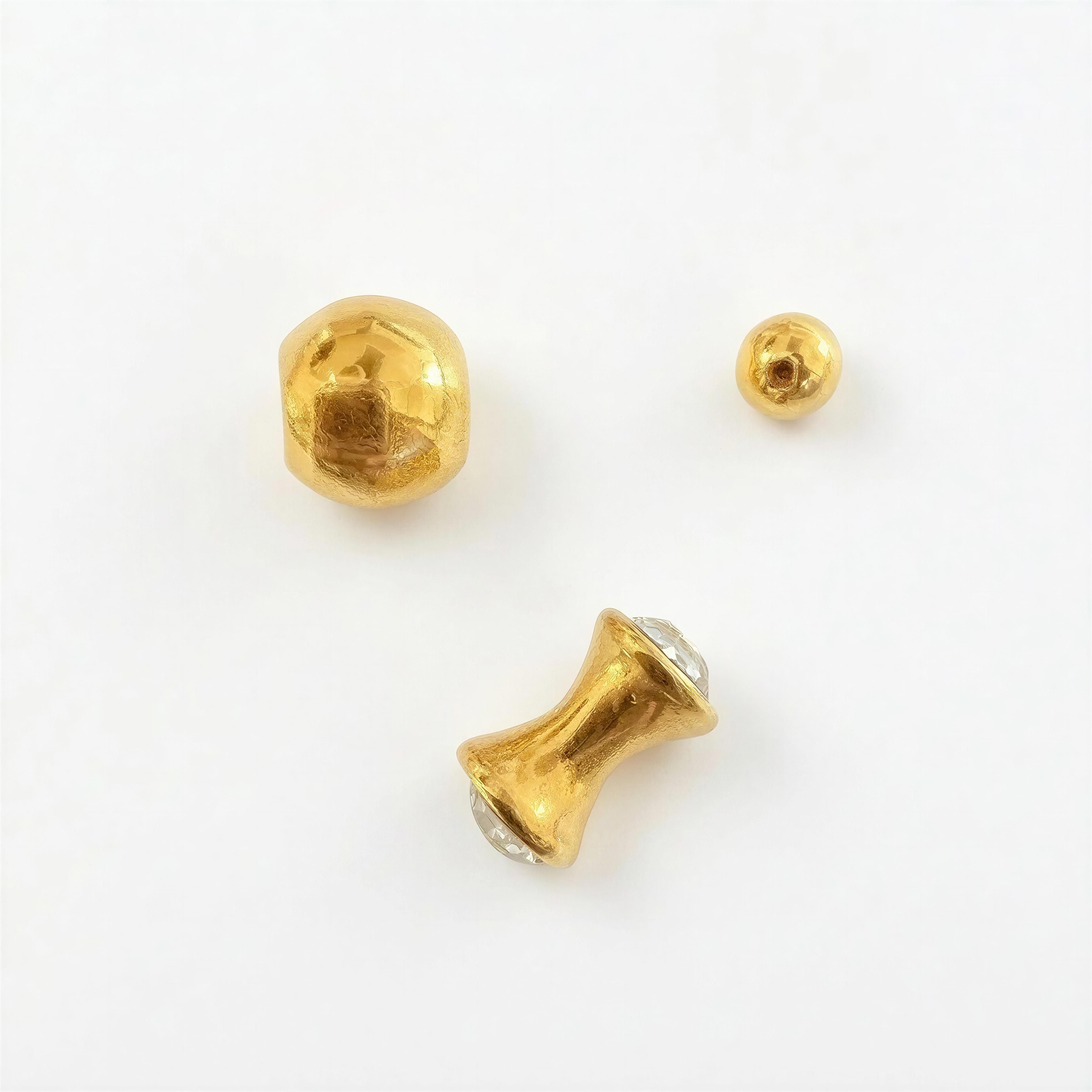 Three gold beads of varying shapes and sizes with a polished finish on a white background, showcasing the XX ÉLÉGANCE - Golden Éclat designer bracelet collection.