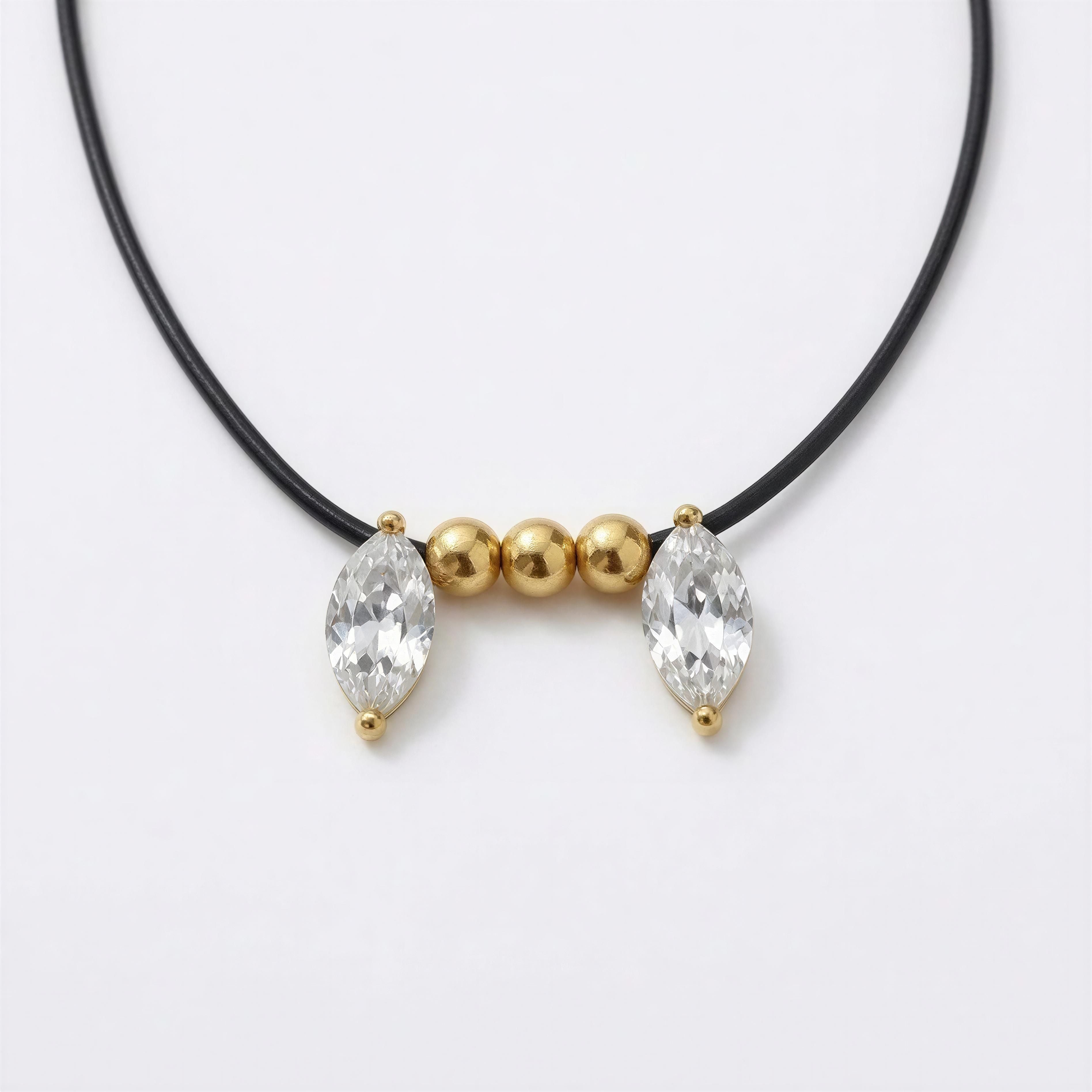 Minimalist black cord necklace featuring two marquise-shaped clear crystals and three polished gold beads, part of the XX ÉLÉGANCE – LUMIÈRE D’OR collection.