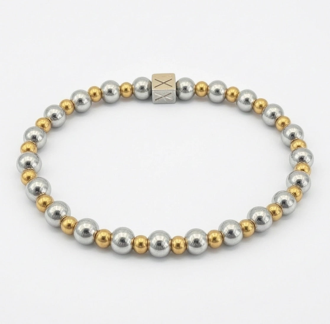 A sleek bracelet featuring alternating polished silver and gold beads with a square accent bead, showcasing The Essential Collection - 6mm & 4mm.
